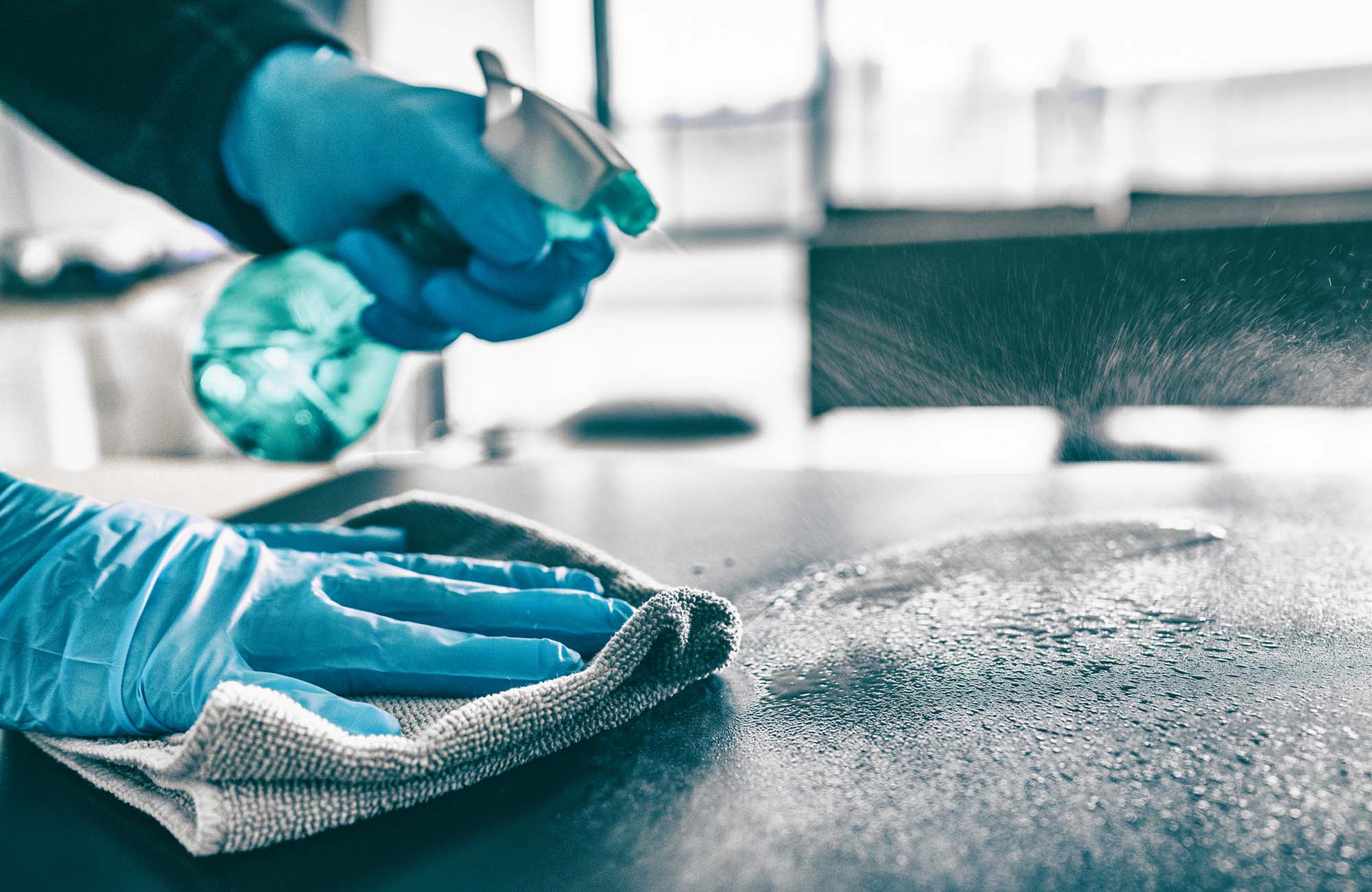 Cleaning home table sanitizing kitchen table surface with disinfectant spray bottle washing surfaces with towel and gloves. COVID-19 prevention sanitizing inside.