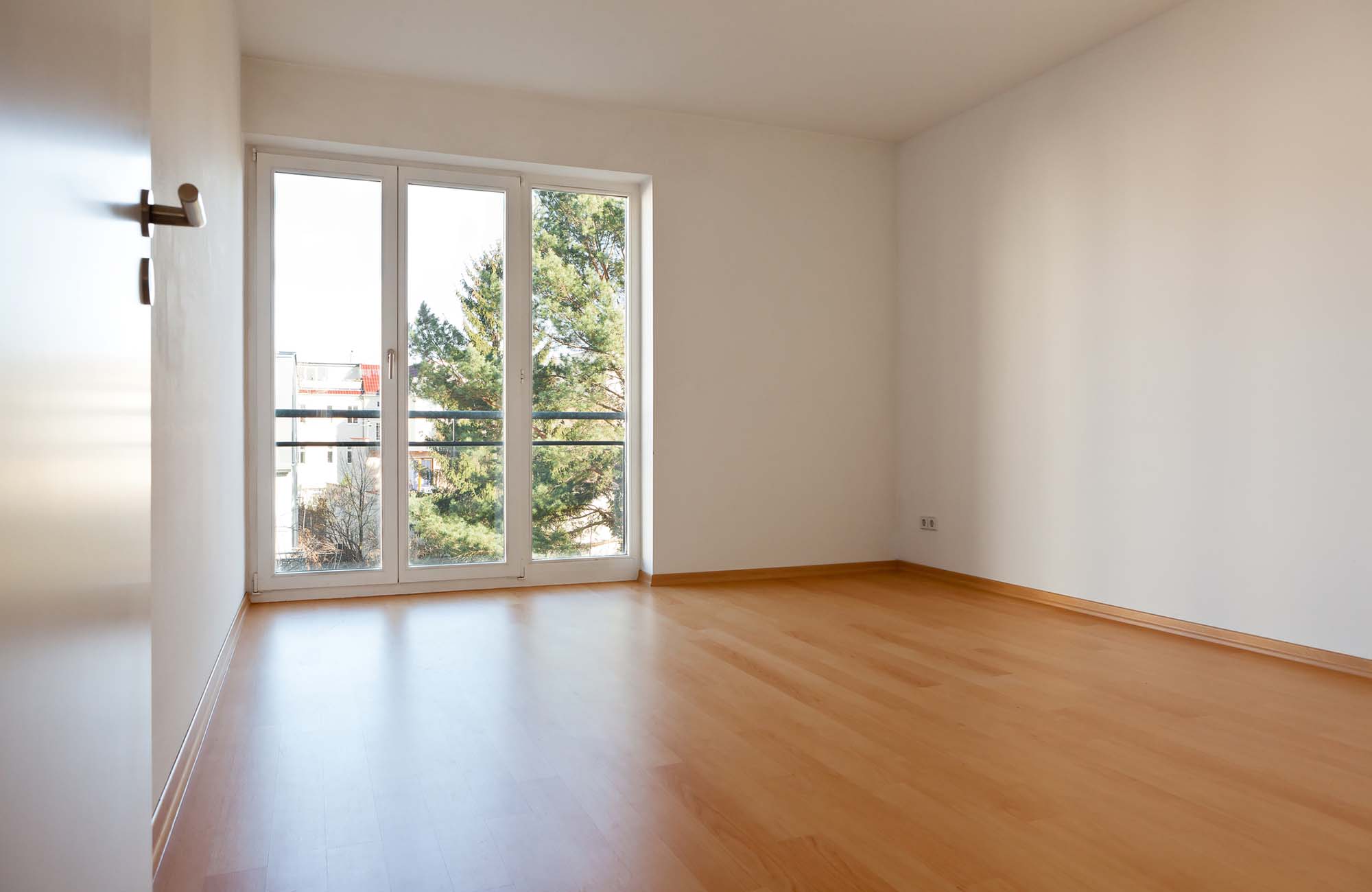 Empty room in apartment. Empty room with parquet and white walls in an apartment
