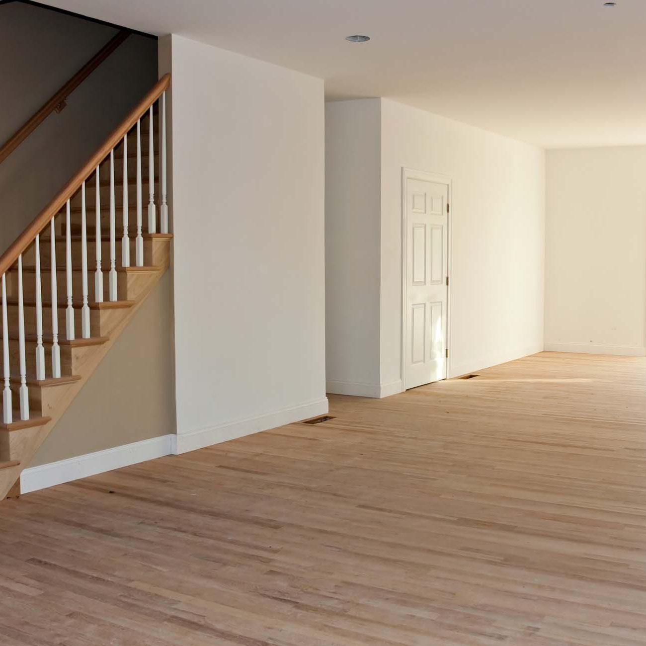 Newly Built House Interior. New home construction interior room with unfinished wood floors stairway and railings. Electrical and hvac connections also are partially unfinished.